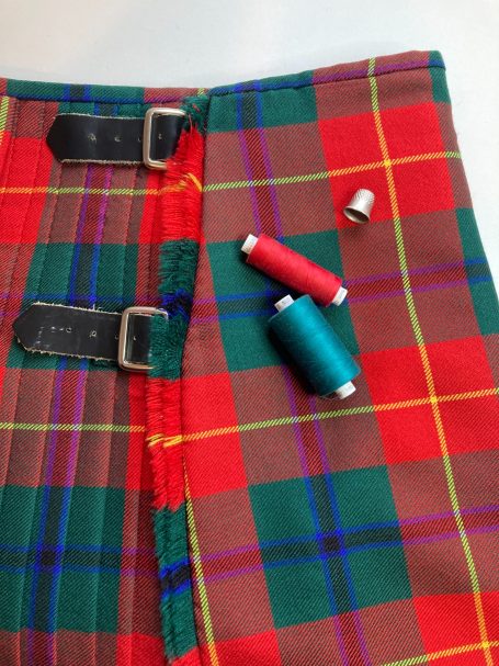 Tartan kilt on a table with thread, showing waist adjustment and widening work for customer in Motherwell