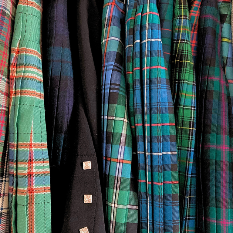 A variety of kilts displayed in a row, showcasing different colours and patterns.