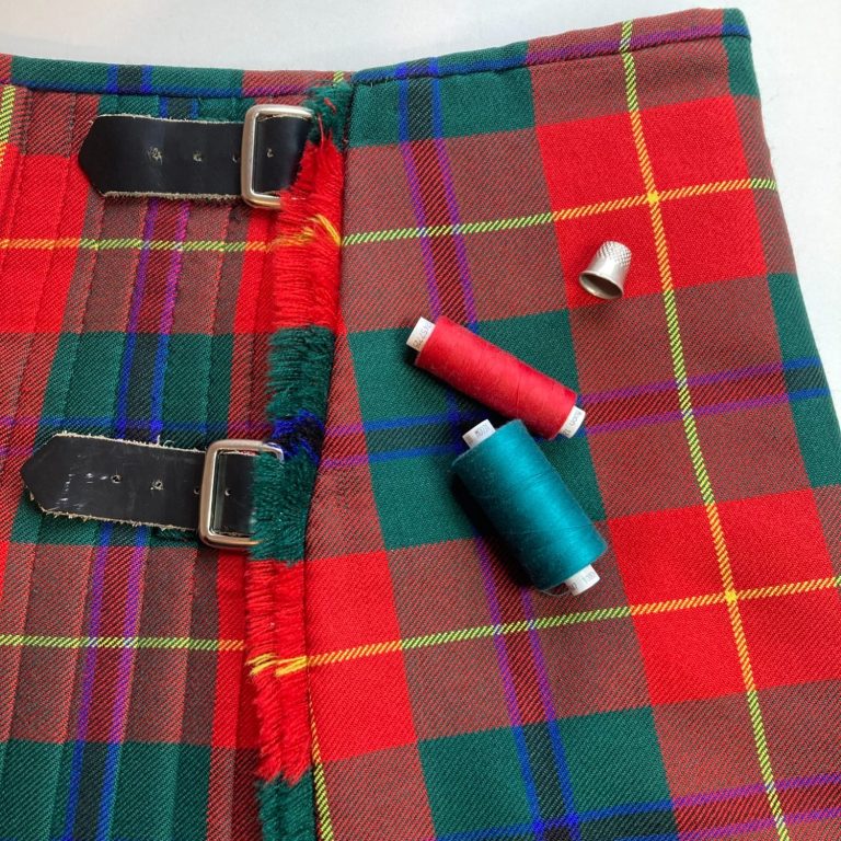 kilt laid out with straps and sewing tools during alteration work